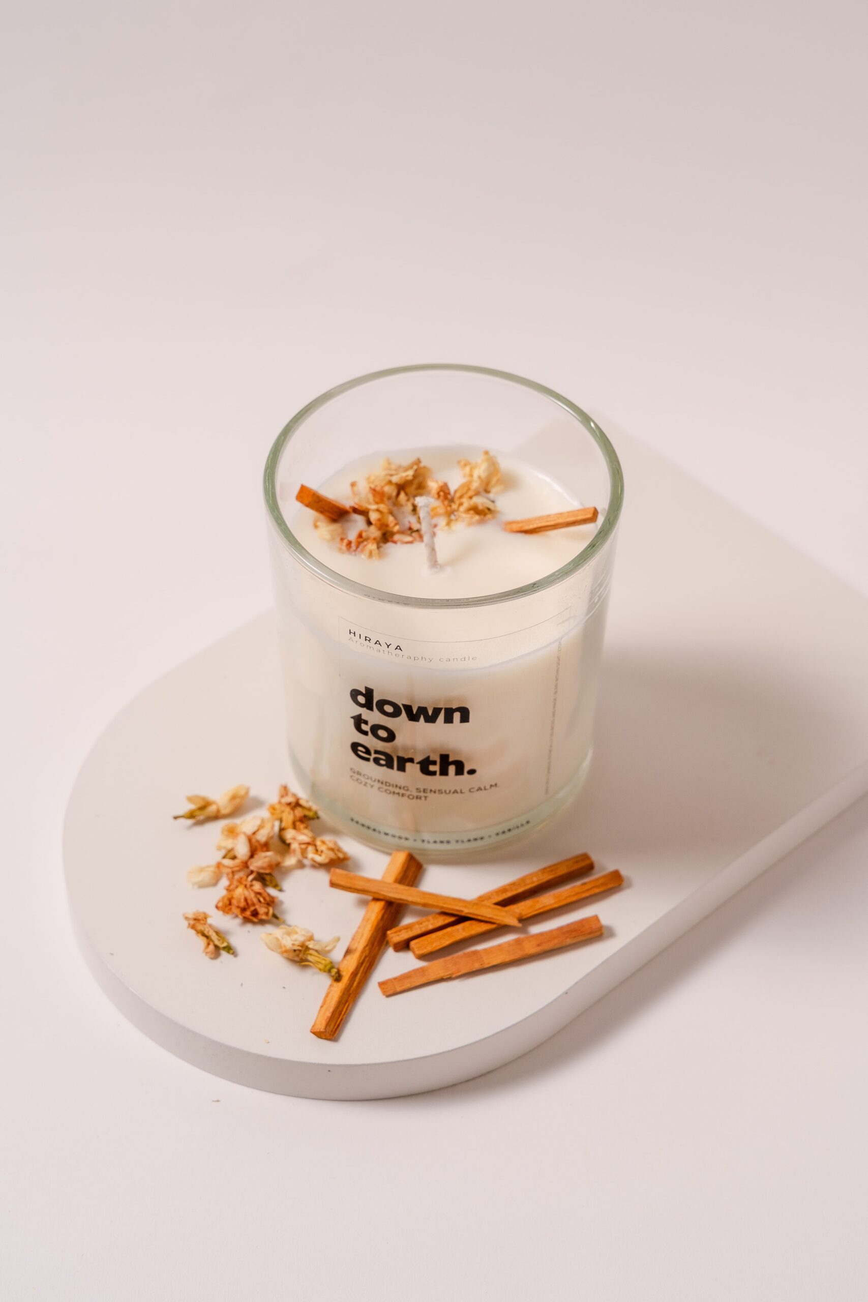 Top view of sandalwood, ylang‑ylang, and vanilla candle showing dried botanicals and earthy toppings